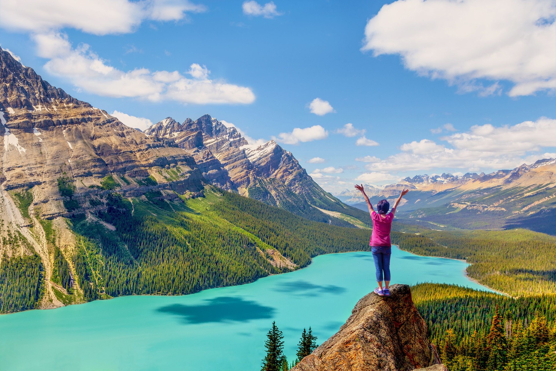 Woman on the pinnacle of Bow Summit with stunning view of Peyto Lake famous for its bright turquoise colored waters in the summer.